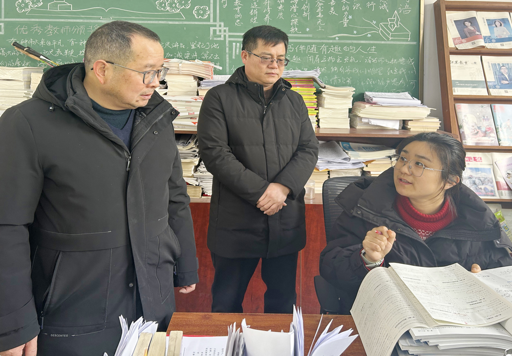 刘荣淦校长（中）带着责任督学（左）向老师了解学生作业布置和批改情况